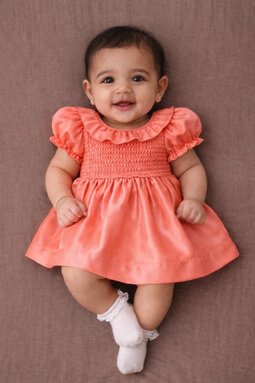 Smiling baby girl in coral puff-sleeve ruffle dress